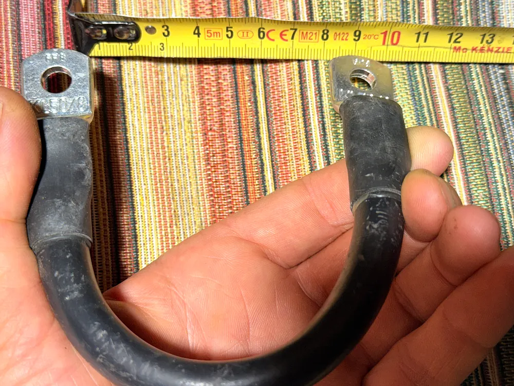 Konfektioniertes 50mm² Batteriekabel im 180°-Bogen um die Hand gelegt, Maßband darüber zeigt den engen Biegeradius